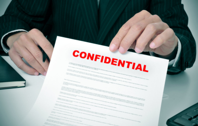 a man wearing a suit showing a document with the text confidential written in it